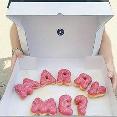 a box filled with pink donuts sitting on top of a table