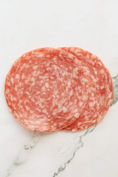 two slices of salami on a marble surface