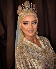 a woman wearing a gold and white dress with a tiara on her head, smiling at the camera