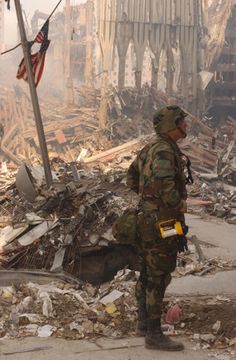 a soldier standing in front of a destroyed building