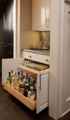 an open cabinet filled with liquor bottles in a kitchen