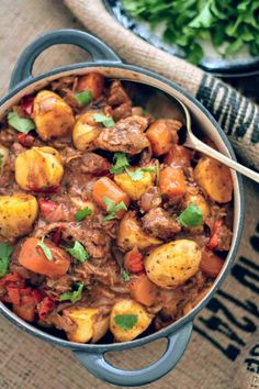 a pot filled with stew and potatoes on top of a table