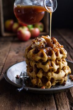 a stack of waffles sitting on top of a plate with syrup being drizzled over them