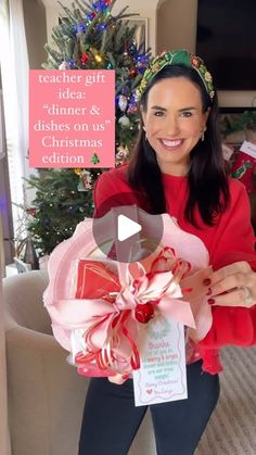 a woman holding a christmas present in front of a christmas tree