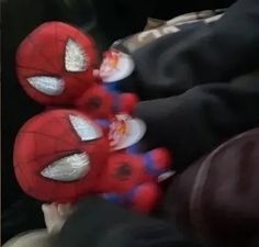 two spider - man stuffed animals sitting on someone's lap