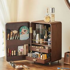 an open wooden box on a table with cosmetics and other items in the case next to it