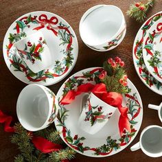 a table topped with plates and cups covered in christmas decorations on top of a wooden table