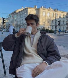 a man sitting at a table drinking from a cup