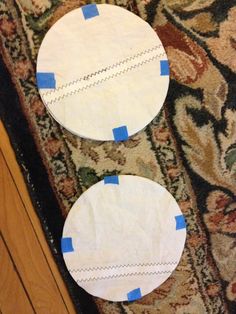 two paper plates sitting on top of a rug next to a wooden table with blue tape