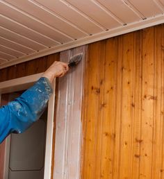 a man with a paintbrush painting the side of a wooden wall in his home