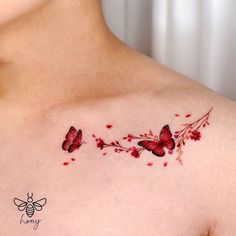 a woman's chest with red butterflies and flowers on the back of her shoulder