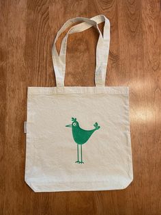 Organic cotton tote bag with green bird printed on both sides, green bird design tote, pre-shrunk, gusseted, natural organic cotton, 13.5 inch X 13.25 inch. Handles are 12 inches long. Eco-friendly Green Tote Bag, Eco-friendly Green Shoulder Bag, Green Eco-friendly Canvas Shopping Bag, Eco-friendly Green Canvas Shopping Bag, Green Tote Bag With Eco-friendly Ink, Green Canvas Gift Bag, Green Canvas Bag With Eco-friendly Ink As Gift, Green Eco-friendly Canvas Tote Bag, Green Eco-friendly Tote Canvas Bag