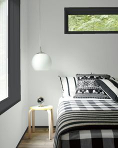 a bedroom with black and white bedding, windows, and a lamp hanging from the ceiling