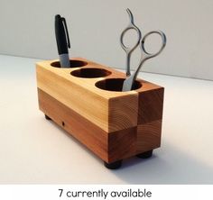 two pairs of scissors are in a wooden holder with three holes for toothbrushes