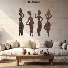 three wooden figures are hanging on the wall above a white couch and coffee table in a living room