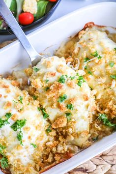 a casserole dish with meat, cheese and vegetables in it next to a bowl of salad