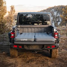 the back end of a jeep parked on top of a dirt field