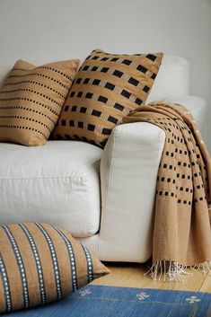 a white couch with pillows on it and a blue rug in front of the couch