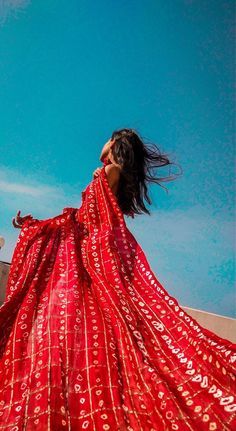 a woman in a long red dress flying through the air with her hair blowing back