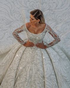 a woman in a white wedding dress with sequins on the skirt and long sleeves