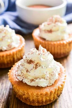 three small desserts with whipped cream and cinnamon sprinkles on wooden table