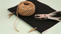 a spool of twine next to a pair of scissors on top of a piece of black paper