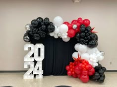 the balloon arch is decorated with black, white and red balloons that spell out new year