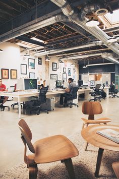 an office filled with desks and chairs next to each other in front of two men working on computers