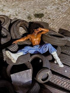 a shirtless man laying on top of old tires