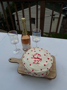 a cake on a table with two wine glasses and a bottle in front of it