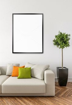 a living room with a white couch and green pillows on the floor next to a potted plant