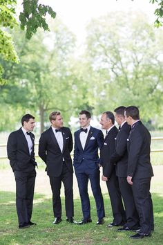 a group of men in tuxedos standing next to each other on the grass