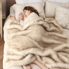 a woman laying on top of a bed under a blanket