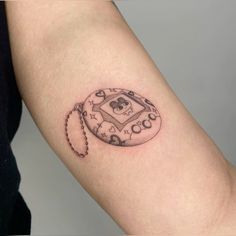 a small tattoo on the arm of a person with a skull and keychain