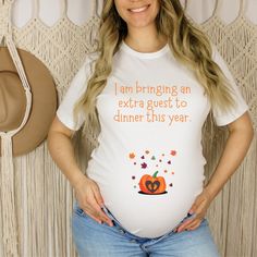 I'm bringing and extra guest to dinner this year, Fall Thanksgiving Pregnancy Announcement Maternity T-shirt. Announce your pregnancy with this cute This is the popular and soft Bella + Canvas 3001 Unisex T-shirt , not a maternity fitted shirt, so order a few sizes up to make room for your growing baby belly. This is a design I created for my shop, and you will only find it here. * Solid colors are 100% Airlume combed and ring-spun cotton * Ash color is 99% combed and ring-spun cotton, 1% polyester * Heather colors are 52% combed and ring-spun cotton, 48% polyester * Athletic and Black Heather are 90% combed and ring-spun cotton, 10% polyester * Fabric weight: 4.2 oz/yd² (142 g/m²) * Pre-shrunk fabric * Unisex Sizing and Fit - If you prefer a loose or oversized fit, order a size up. Averag Maternity Graphic Tee With Short Sleeve, Maternity T-shirt With Funny Text, Maternity T-shirt With Funny Text And Short Sleeves, Maternity Short Sleeve T-shirt With Funny Text, Bump Friendly White Short Sleeve T-shirt, Maternity Graphic T-shirt With Crew Neck, Maternity Crew Neck T-shirt, Maternity Graphic Tee With Crew Neck, White Maternity Crew Neck T-shirt