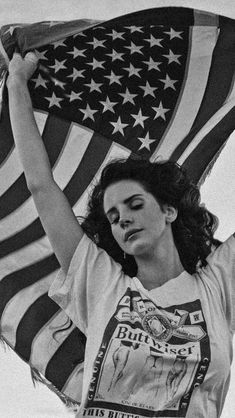 a woman holding an american flag in front of her head and shoulders, with one arm raised