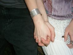 two people holding hands while standing next to each other with rings on their fingertipss