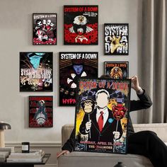 a man sitting on a couch in front of a bunch of posters