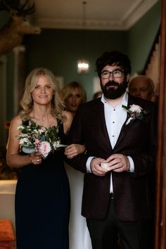 a man and woman standing next to each other in front of a doorway with flowers