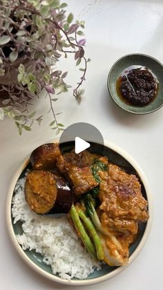 a plate with rice, asparagus and meat on it next to a bowl of sauce