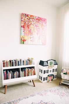 a living room with bookshelf and toy houses on the floor next to it