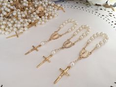 a bunch of pearls and cross necklaces sitting on a table next to some flowers