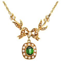 Discover the elegance of the Edwardian era with our Antique Pearl & Tourmaline Necklace, a timeless piece of exquisite craftsmanship. This stunning necklace features an ornate, oval-shaped faceted dark green tourmaline, beautifully bezel-set and framed with delicate seed pearls, evoking the sophisticated glamour of a bygone era. Suspended beneath a stylized bow and flowers, intricately set with seed pearls, this piece captures the intricate detail and romantic design characteristic of Edwardian The Edwardian Era, Edwardian Jewelry, Romantic Design, Tourmaline Necklace, Bygone Era, Edwardian Era, Jewel Box, Seed Pearl, Stunning Necklace