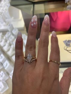 a woman's hand with pink and white manicured nails holding a diamond ring