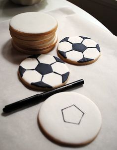 cookies decorated with black and white soccer balls are sitting on a table next to a cup