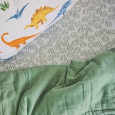 two sheets with dinosaurs on them are laying next to each other in the same bed