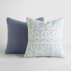 two blue and white pillows sitting next to each other