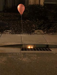 a hole in the ground with a balloon attached to it and two candles lit inside