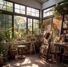 an artist's studio with lots of plants and paintings