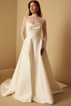 a woman in a white wedding dress posing for the camera with her hands on her hips